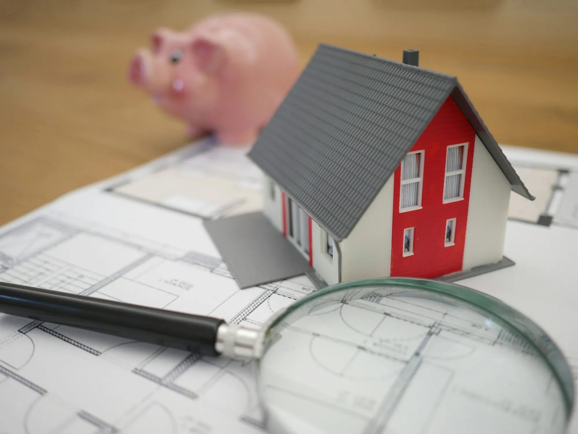 Model house and magnifying glass on top of blueprints