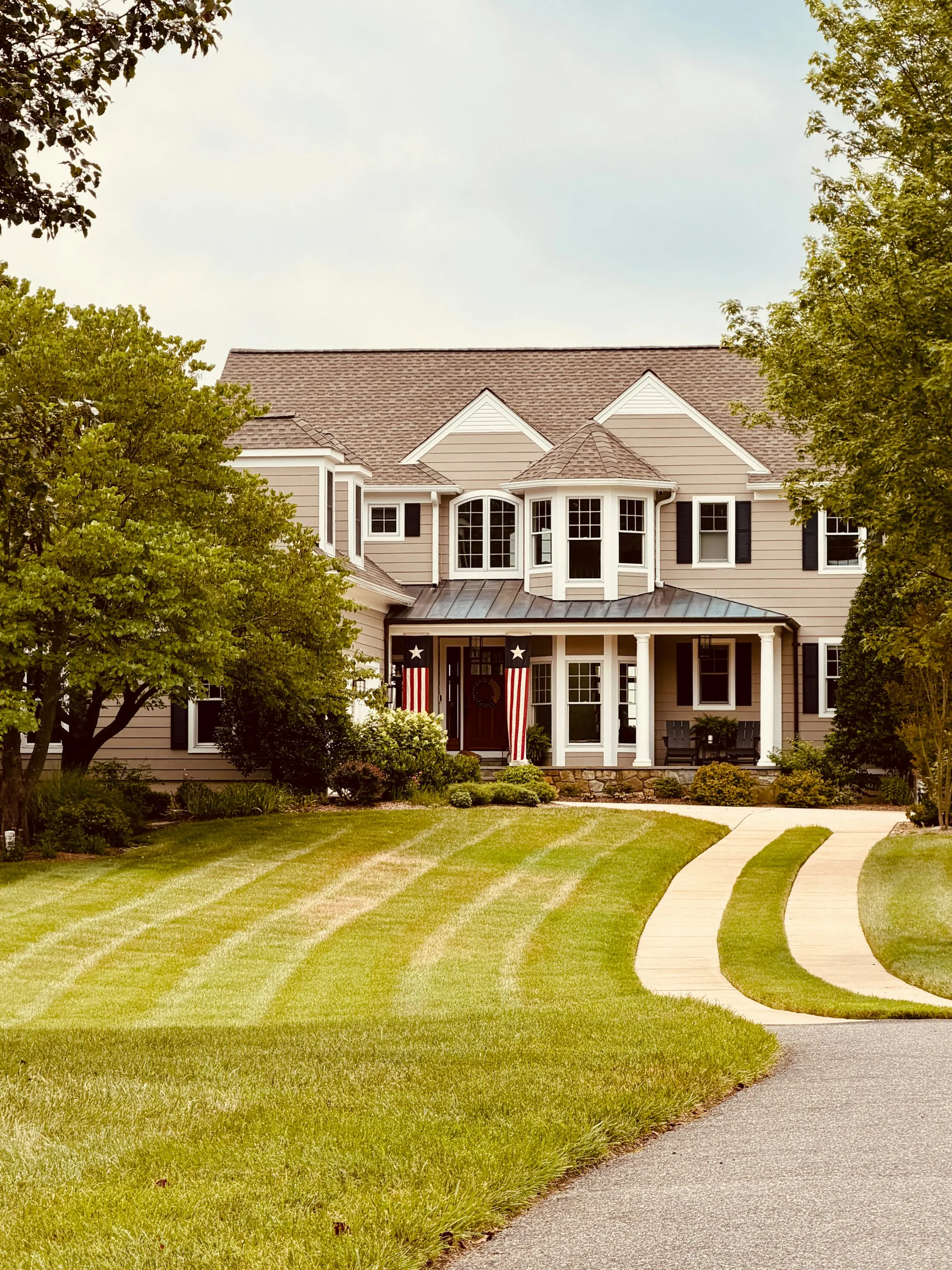 Large beige home with a curved front walk and manicured lawn