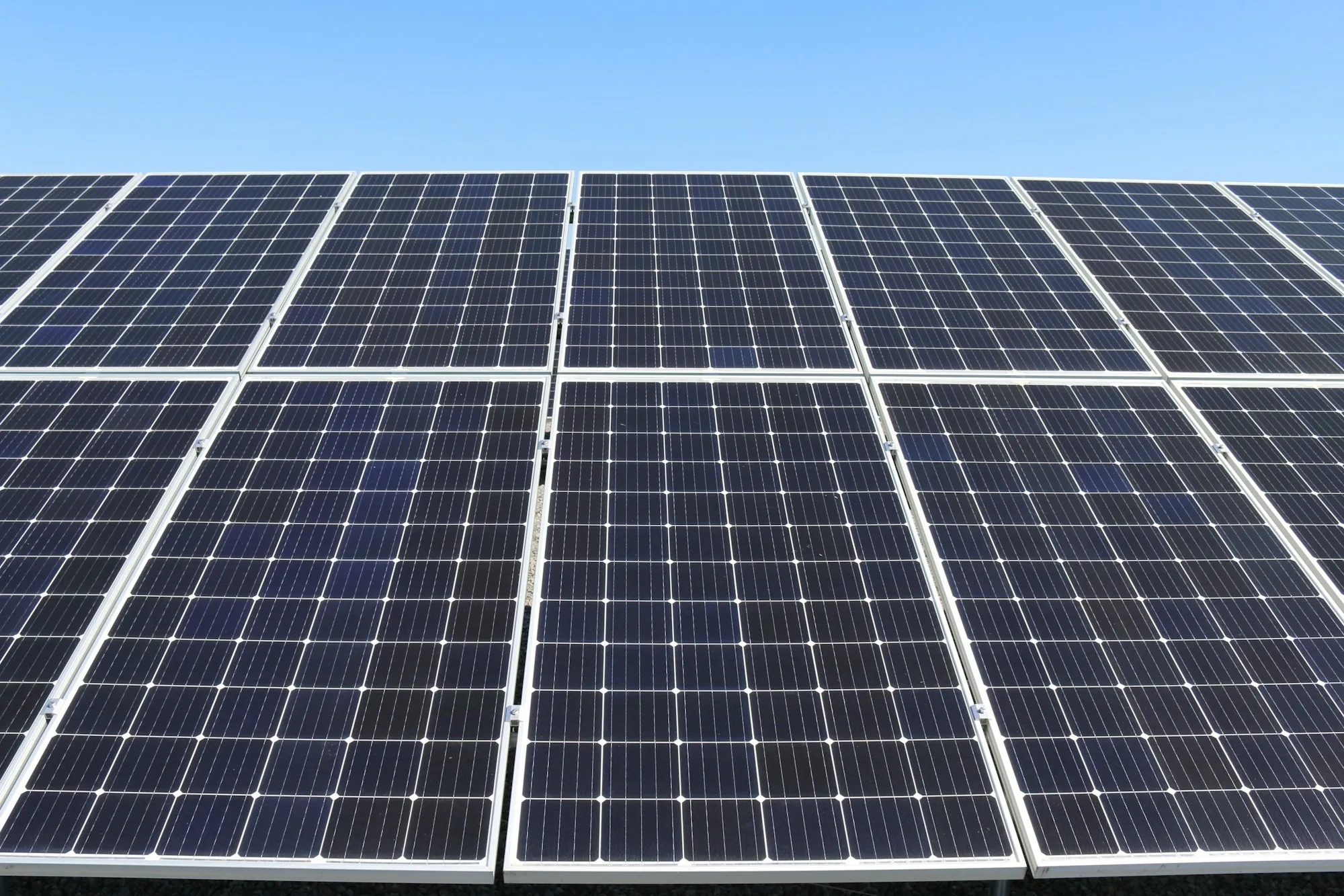 Grid of blue solar panels on a mounting rack under a clear sky, the kind of array tested after reinstall on a Homewood roof