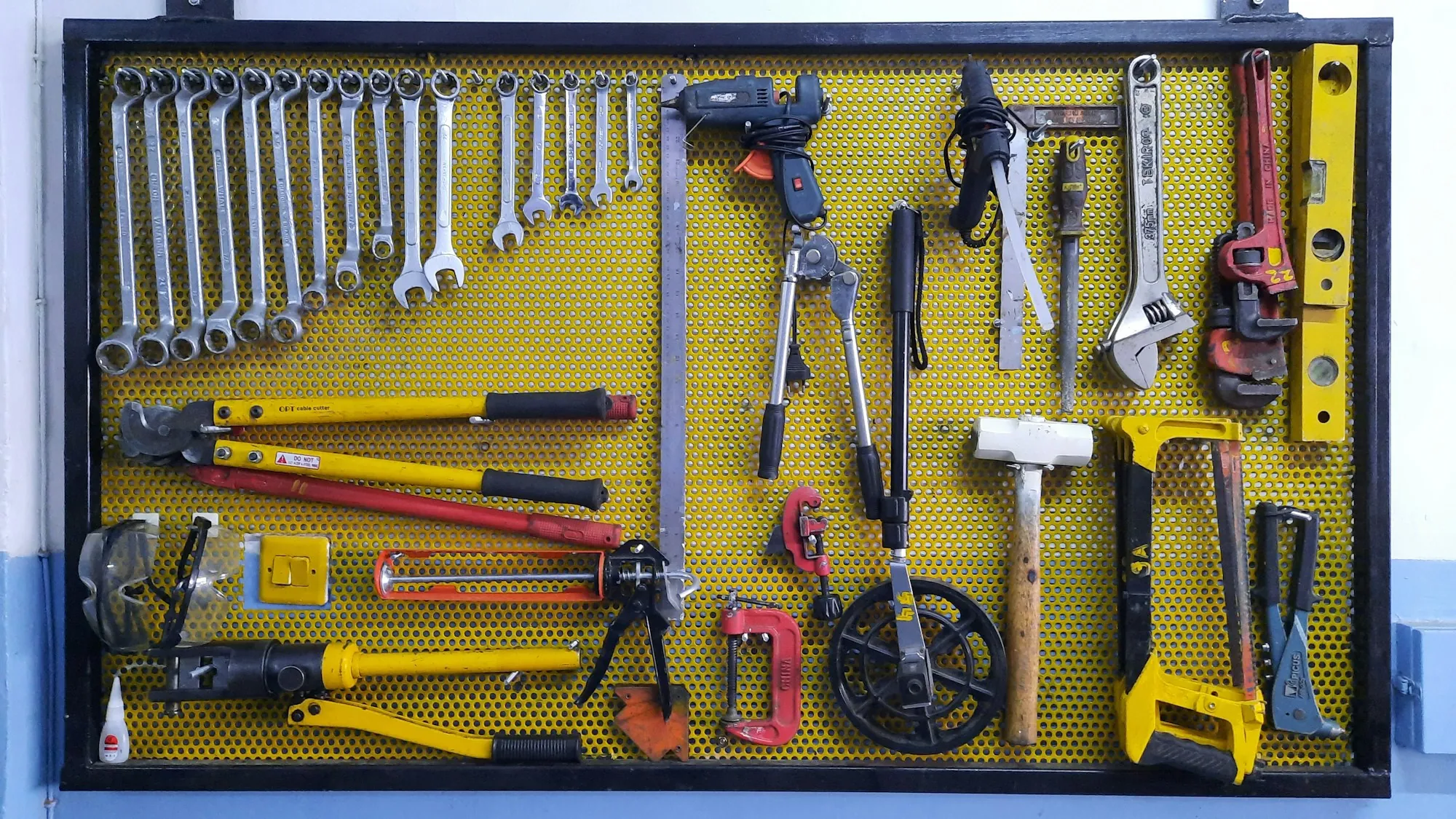 Yellow pegboard wall with wrenches, pliers and hand tools